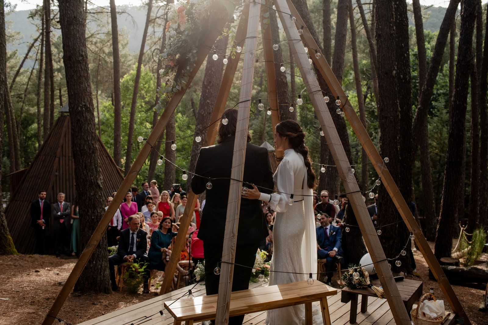 Ceremonia de boda en un claro del pinar, con sillas y altar de madera