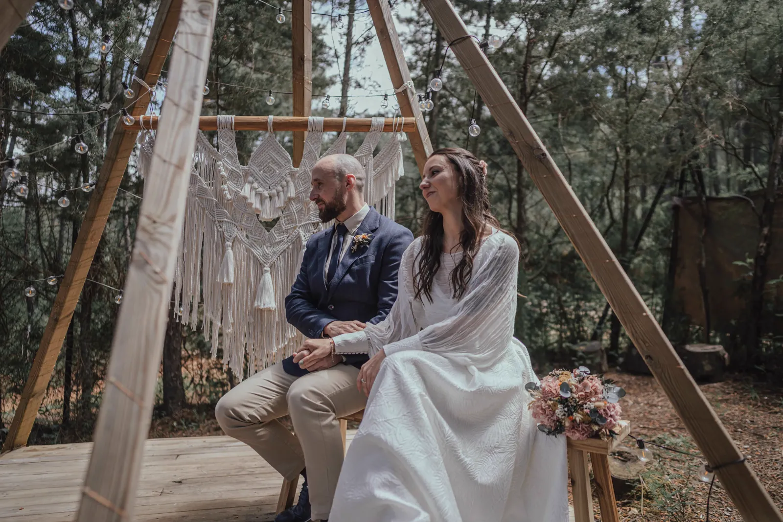 Pareja sentada en el altar-teepee triangular bajo los pinos