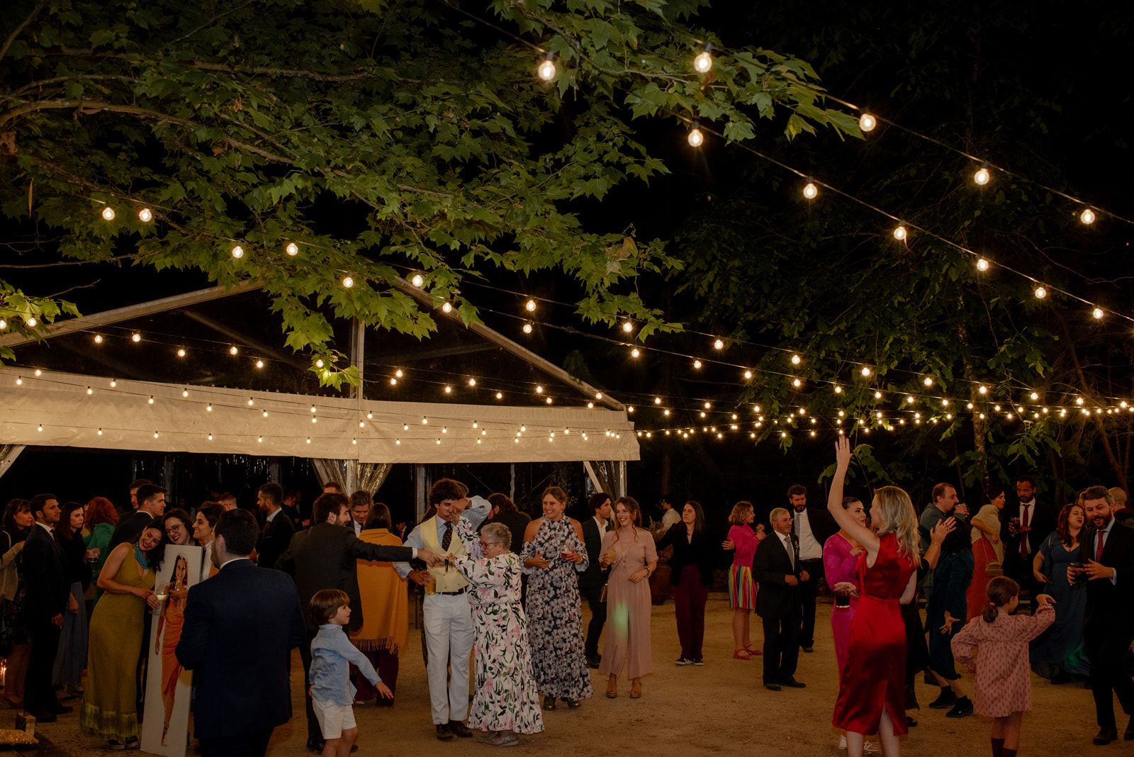 Invitados bailando en la pista montada entre los árboles durante la fiesta nocturna