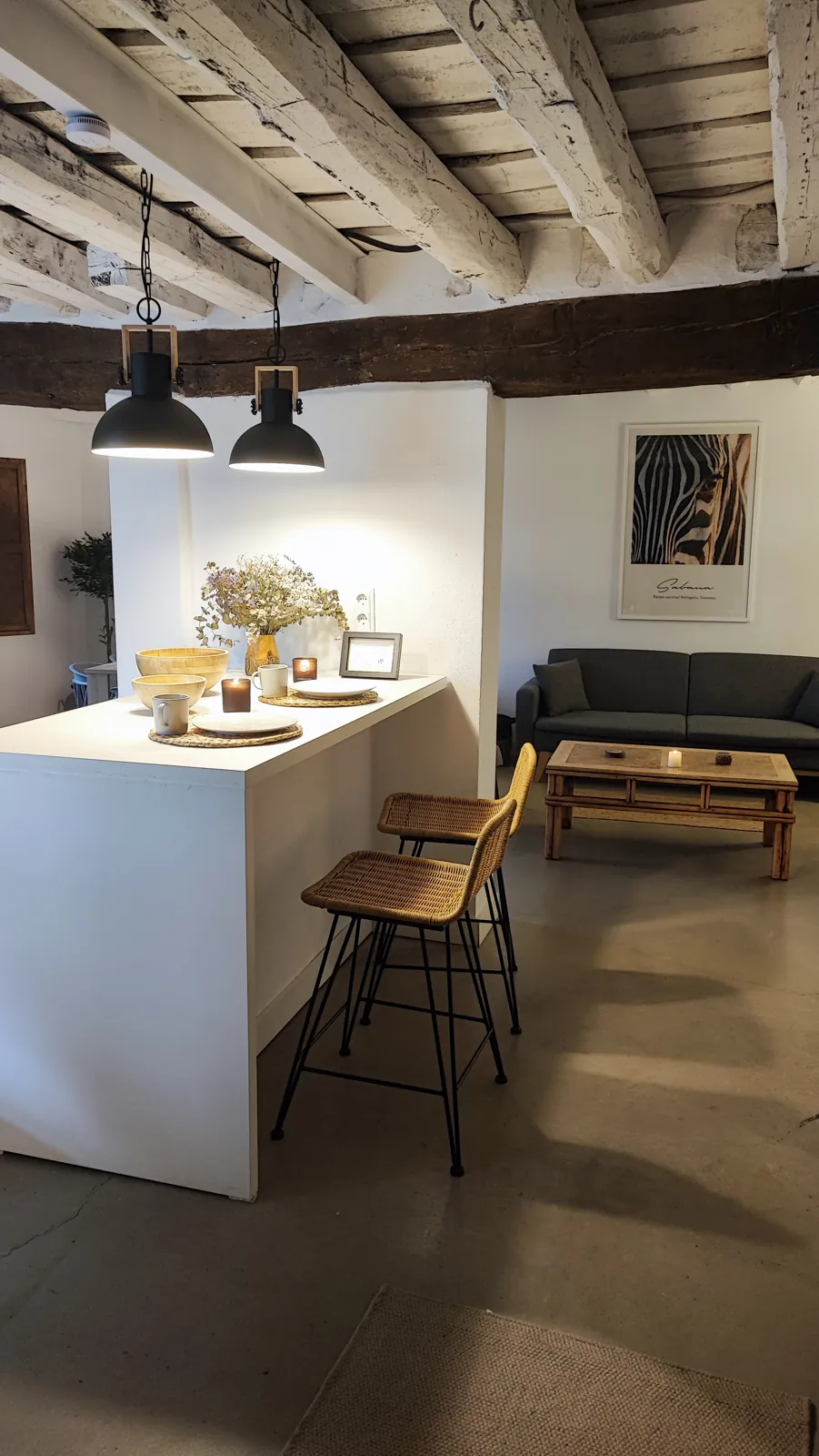La cocina de Casa Chía con barra y taburetes, el salón al fondo y las vigas de madera a la vista