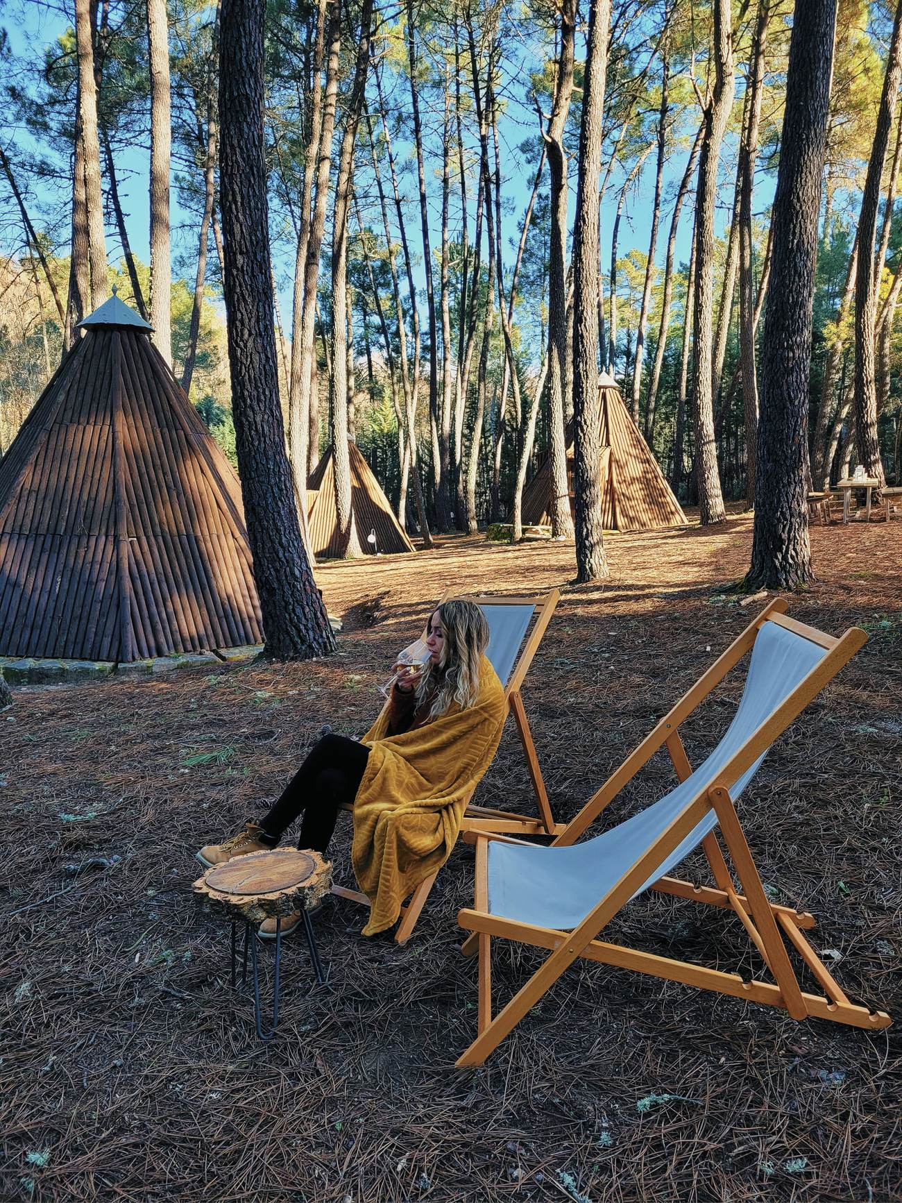 Rincón chill en el porche de los tipis, entre los pinos del glamping