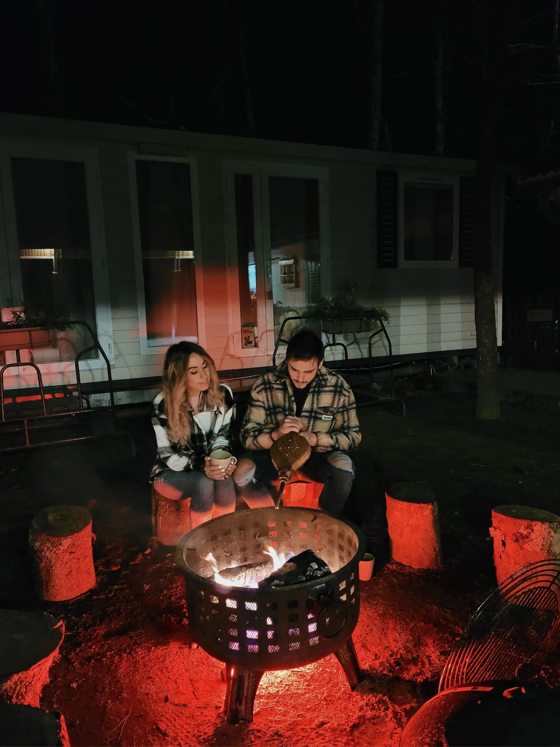 Grupo de amigos alrededor de la fogata frente a los tipis en la noche