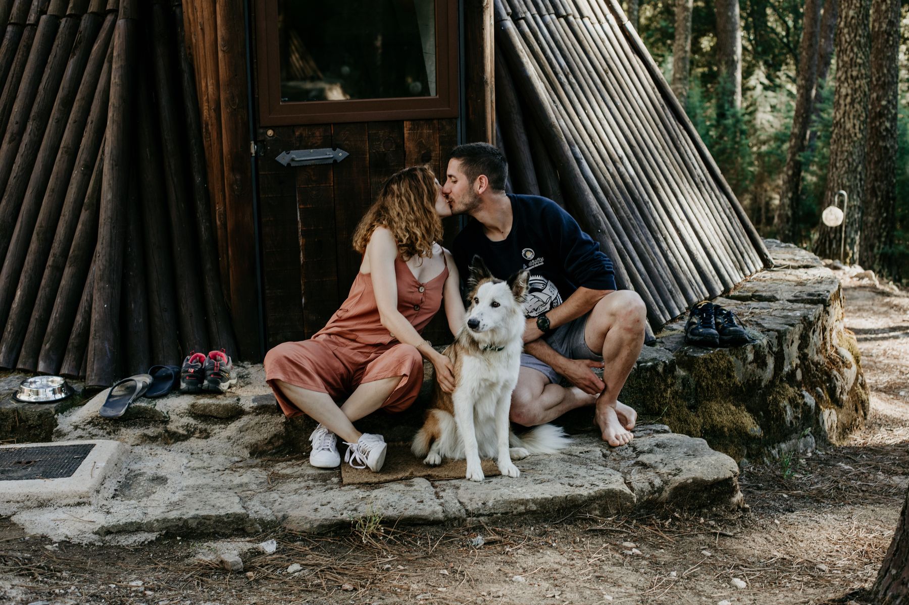 Pareja con su perro descansando en el porche de un tipi