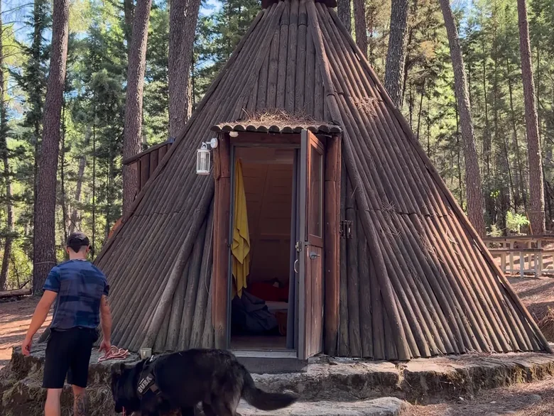 Llegando al tipi con el perro Huésped de espaldas con su perro delante de un tipi con la puerta abierta