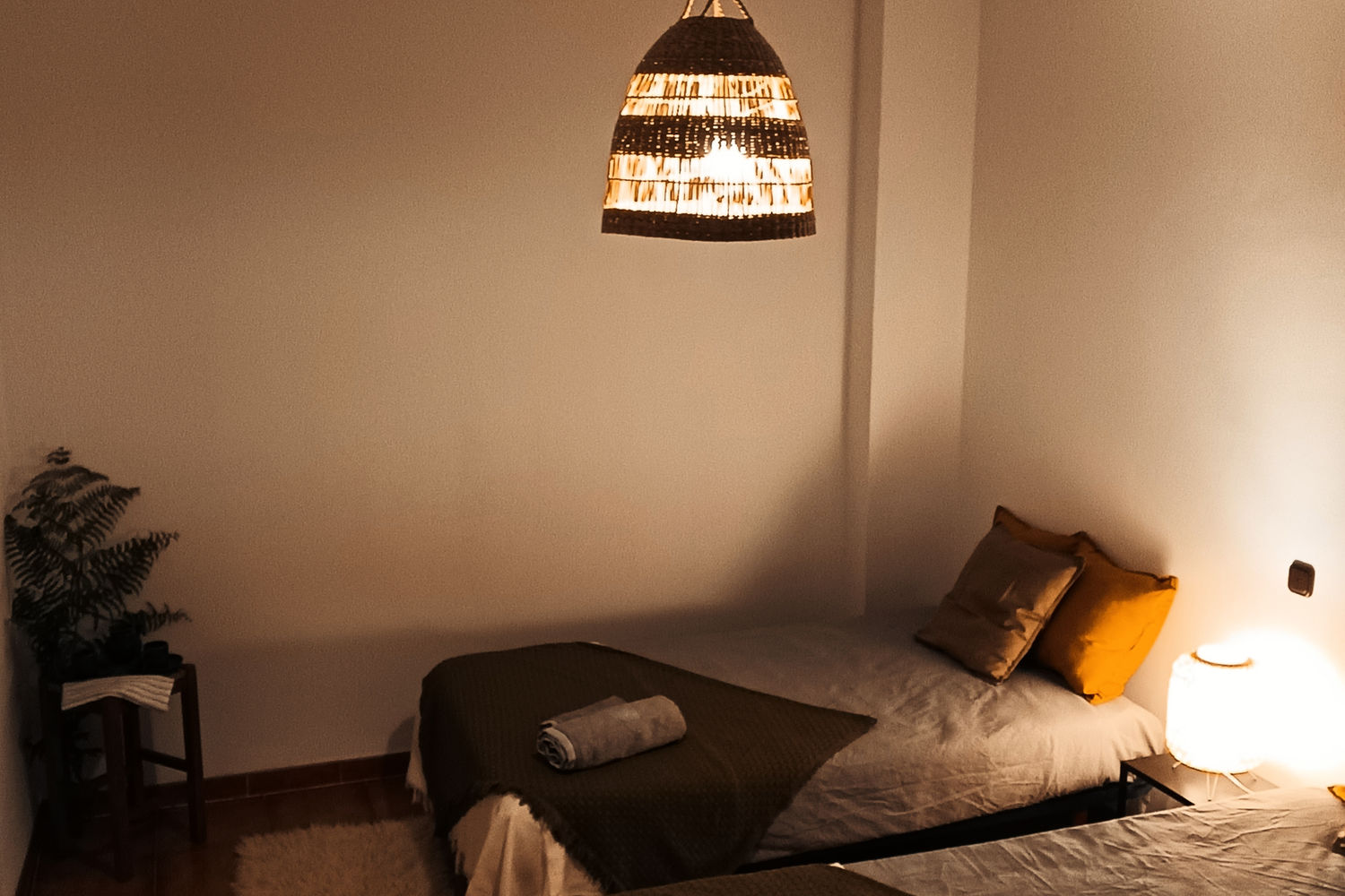 Dormitorio de Villa Moiko con luz cálida y lámpara de fibra natural sobre las camas